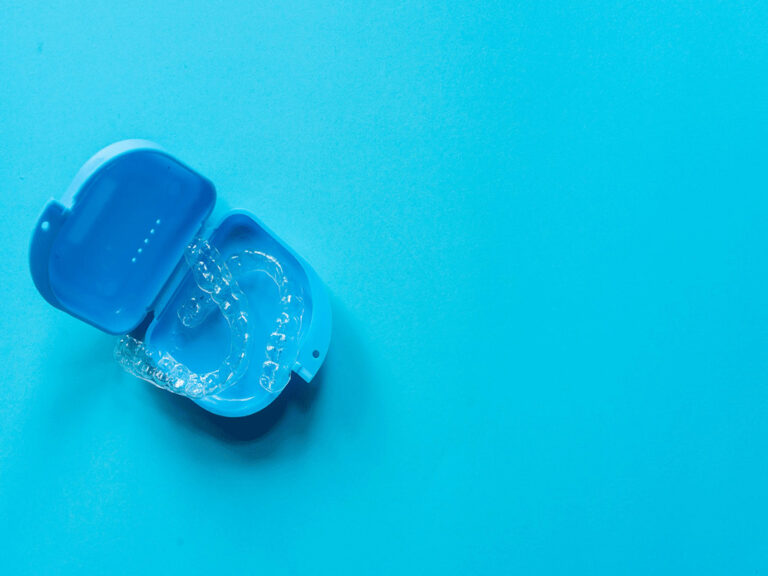 clear aligners in a portable case on a blue background